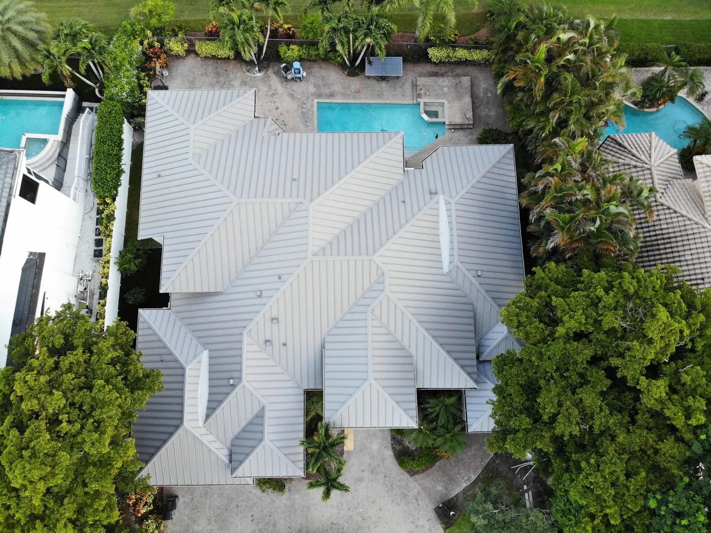Aerial view of a newly installed standing-seam metal roof on a South Florida home with a pool