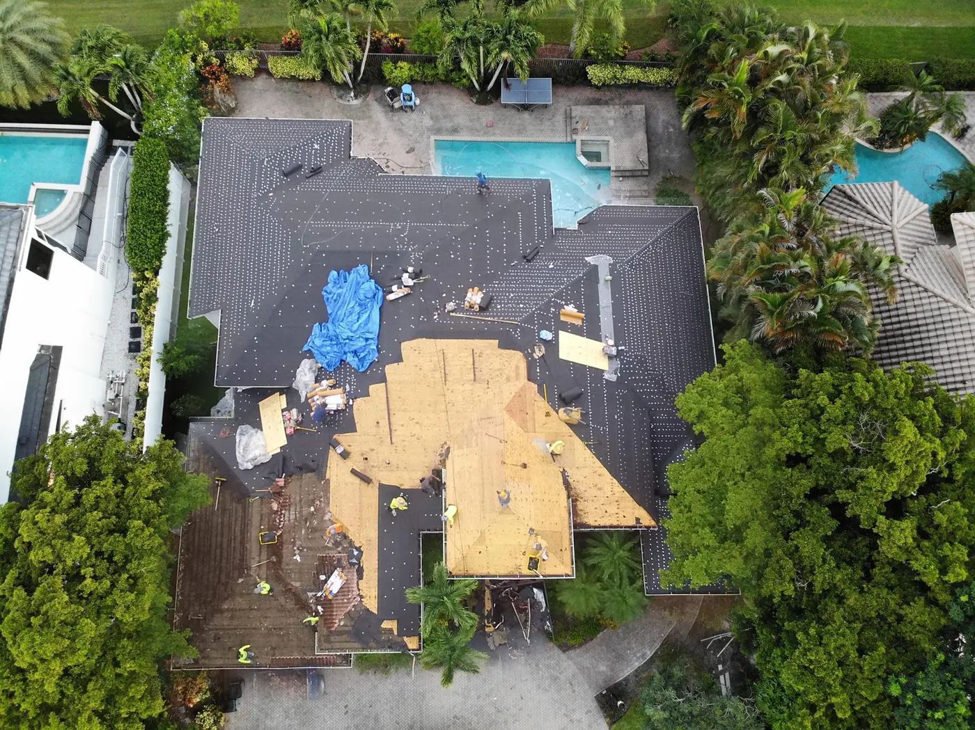 Proper Roofing tear-off in progress: exposed plywood decking and synthetic underlayment on a South Florida home