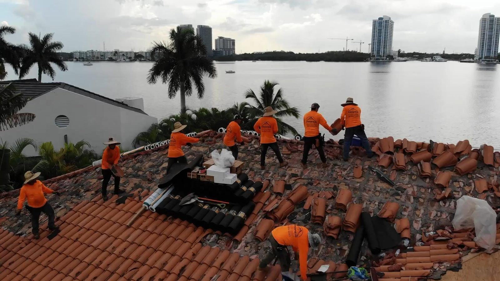 Proper Roofing crew tearing off tile on a Miami-area waterfront home